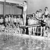 Groupe de jeunes hommes, du moniteur et de deux prêtres autour d'une piscine.